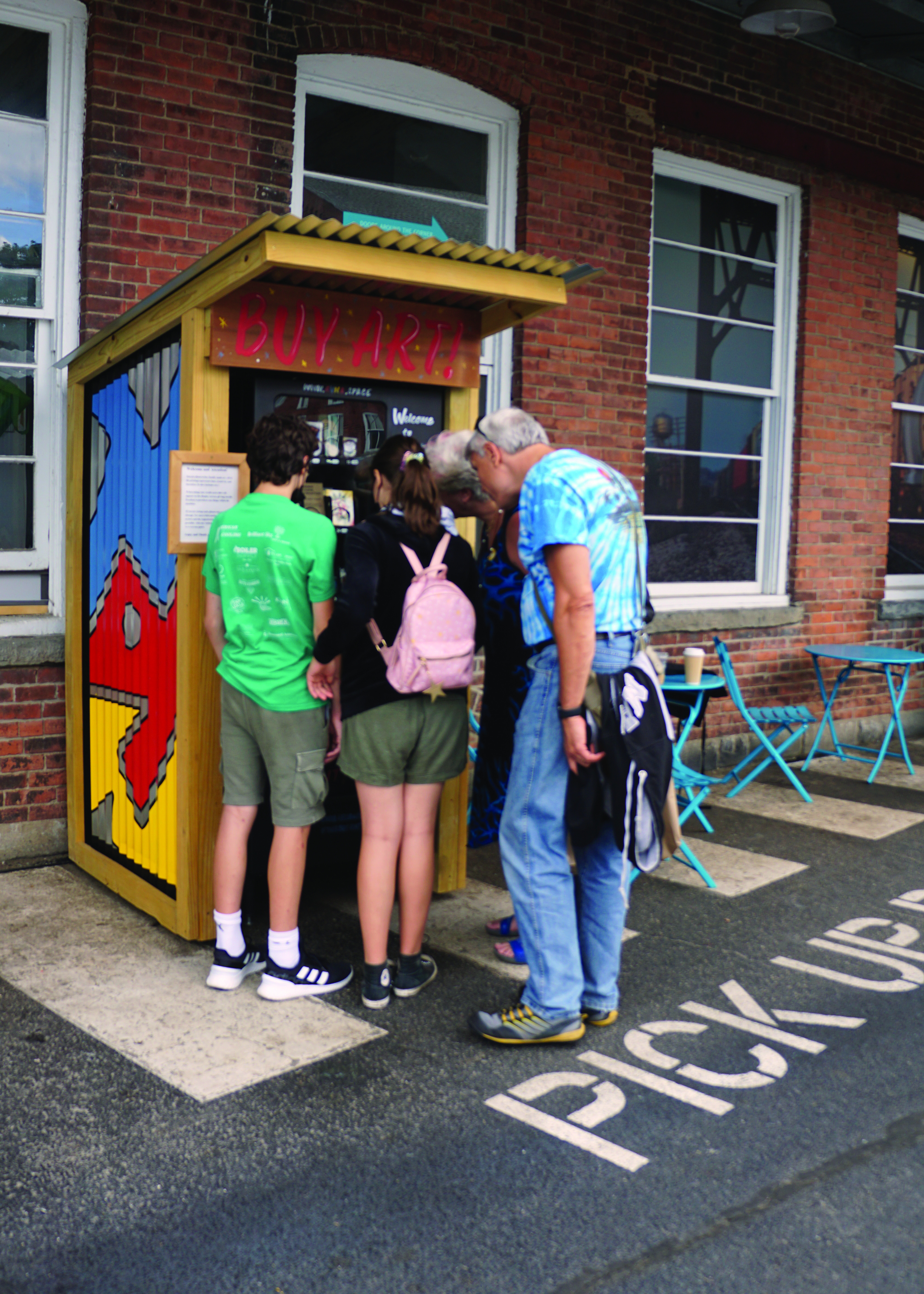 A family visiting Mass MoCA stops by Art Vending North Adams to check out the art, and purchases a piece.